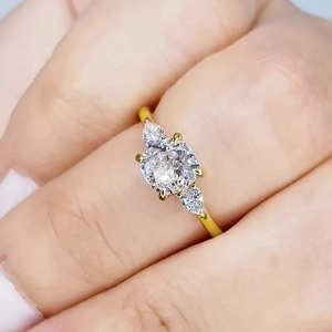 Detail van gouden ring met drie stenen met kussengeslepen en druppelvormige zirkonia