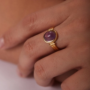 Gros plan d'une bague en or 18 carats avec gemme violette ovale et anneau texturé rétro