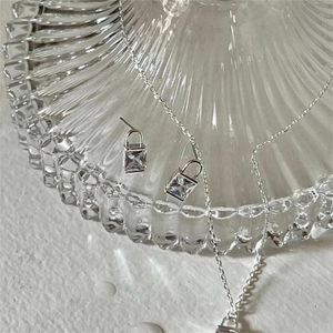 Detail view of silver padlock jewelry set featuring square zircon stones on necklace and earrings
