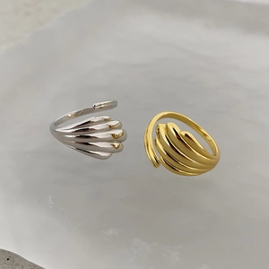 Detailed close-up of shell-textured gold and silver adjustable rings on white stone