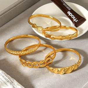 Five assorted 18K gold plated titanium steel bangles set with diverse textures