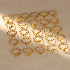 Golden stainless steel adjustable alphabet rings from A to Z on warm plush background