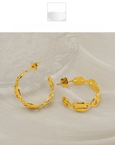 Detailed macro view of golden C-shaped pig nose hoop earrings on elegant white silk background