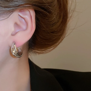 Macro detail of crisscross silver hoop earrings with high-polish finish on model