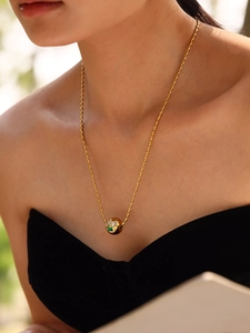 Détail du collier à billes en or 18 carats avec pierre émeraude sur le cou d'un mannequin
