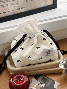 Close-up of white fabric tissue storage bag with black bow patterns and elegant labels