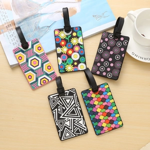 Flat lay of five cute PVC luggage tags with geometric and floral patterns on wood background