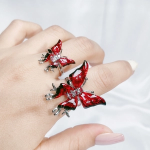 Detailed macro view of silver butterfly rings featuring red and black enamel with zircons