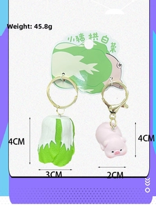 Detail of pink pig and green cabbage keychain with golden metal ring and lobster clasp