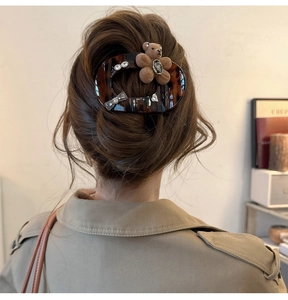 Detail of tortoise shell hair claw with plush bear and rhinestone bow on model hair