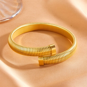 Détail d'un bracelet spirale Tubogas doré sur tissu en soie au fini métal brillant
