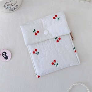 Detail of white quilted cherry print cosmetic bag with snap button closure and soft texture