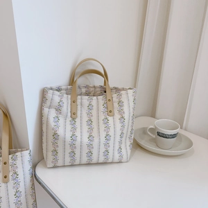 Close-up of floral tote bag featuring sturdy leather handles and metal rivet details
