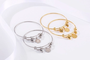 Detailed view of gold and silver steel bangles with coin, heart, and bead charms