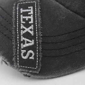 Macro view of distressed charcoal grey cotton fabric with Texas embroidery on baseball cap