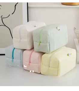 Dettaglio di pochette trucco trapuntate in beige, verde menta e colori pastello