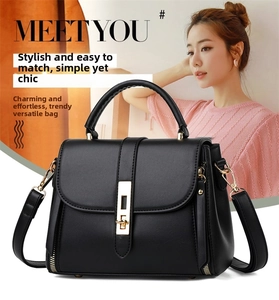 Detail of soft black leather handbag featuring gold metallic buckles and textured finish