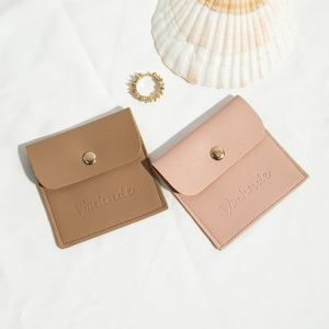 Pink and brown PU leather jewelry pouches with gold snap button on white fabric