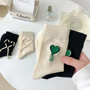 Dettaglio calzini in maglia con ricamo a cuore verde 3D e dettagli con nodo bianco