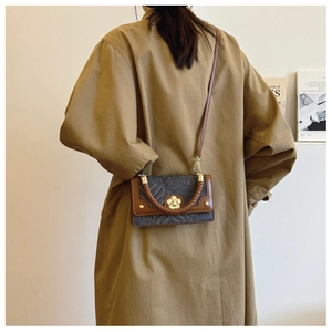 Detail van vintage bruine leren handtas met golfpatroon en metalen bloemgesp