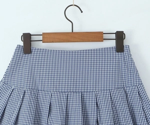Detail of blue and white plaid pleated skirt fabric with uniform pleats on a wooden hanger