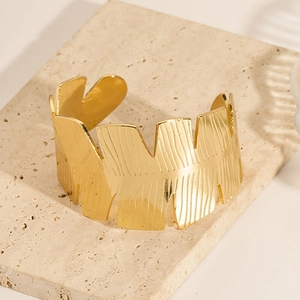 Textured 18K gold-plated stainless steel C-shaped open cuff bracelet on stone