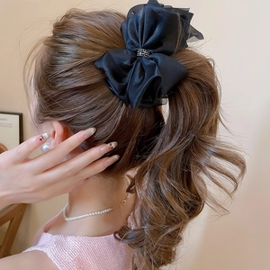 Dettaglio molletta per capelli a fiocco nero con strass luminosi su coda di cavallo alta