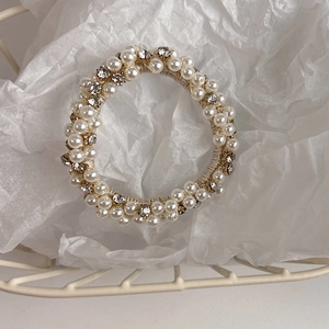 Detailed view of elastic hair tie featuring white pearls and sparkling rhinestones