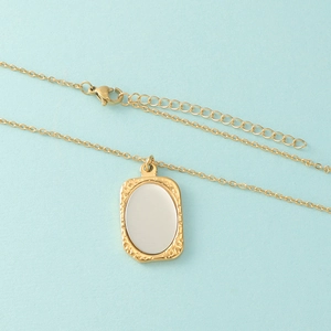 Minimalistische gouden ketting met getextureerd frame en zilveren ovale spiegel hanger