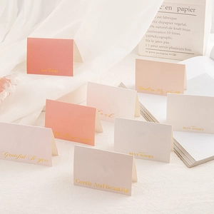 Macro view of pastel greeting cards with gold foil lettering and folded paper texture