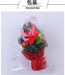 Close-up of mini Christmas tree featuring red petals and golden mesh balls in packaging