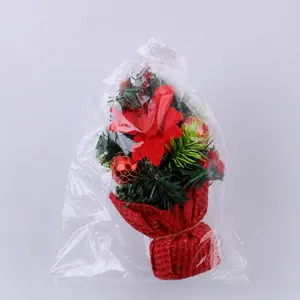 Close-up of mini Christmas tree featuring red petals and golden mesh balls in packaging