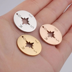 Detail of 20mm stainless steel compass charms in silver, gold and rose gold on a hand