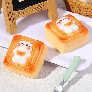 Miniature resin cat-shaped pastry ornaments on a white plate with tiny baking props