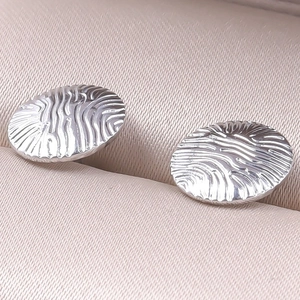 Macro detail of silver stainless steel earrings with irregular wavy streamline texture