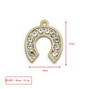 Detail of horseshoe pendant with white rhinestones measuring 21mm by 19mm in gold
