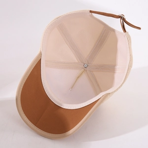 Detailed interior of a beige baby baseball cap showing six-panel stitching and brown strap