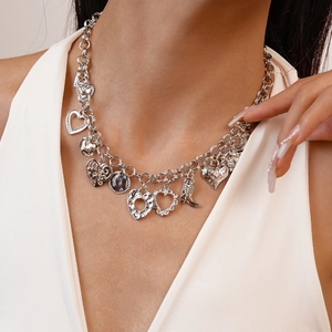 Detail of silver chain necklace featuring heart and cowboy boot pendants on a model neck