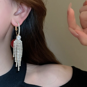 Close-up of golden tassel earrings with sparkling rhinestones worn by a model