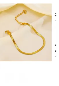 Close-up of flat gold-plated snake chain with lobster clasp on beige silk background