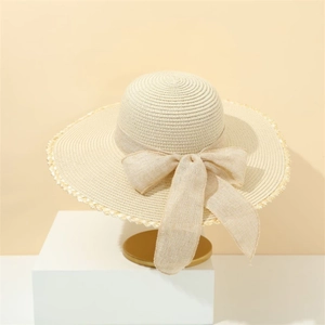 Elegant beige wide-brim straw sun hat with bow and white lace trim on a minimalist stand