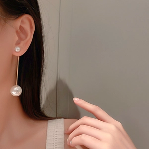 Élégantes boucles d'oreilles pendantes en perles et tige dorée portées par un mannequin