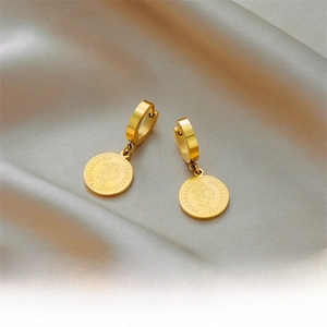 Detail of gold hoop earring with Elizabeth II portrait coin pendant on silk fabric