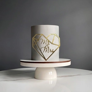 Close-up of golden Mr & Mrs heart cake topper with mirror finish for wedding decor