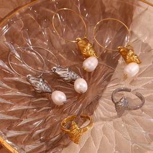 Macro shot of 18K gold plated conch shell rings and pearl earrings on glass tray