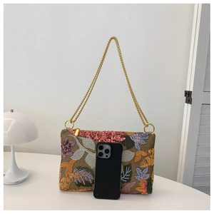 Detail of colorful floral sequin embroidery and golden chain on the elegant evening bag