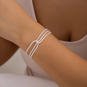 Close-up of layered silver twisted chain bracelet on wrist showing refined metal texture