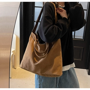 Deep brown tote bag in soft faux suede finish shown on shoulder in a minimalist indoor setting