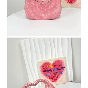 Detail of pink marble acrylic evening bag with rhinestone heart handle and gold hardware