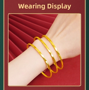Close-up of three gold stacked bangles with geometric faceted texture on a model wrist